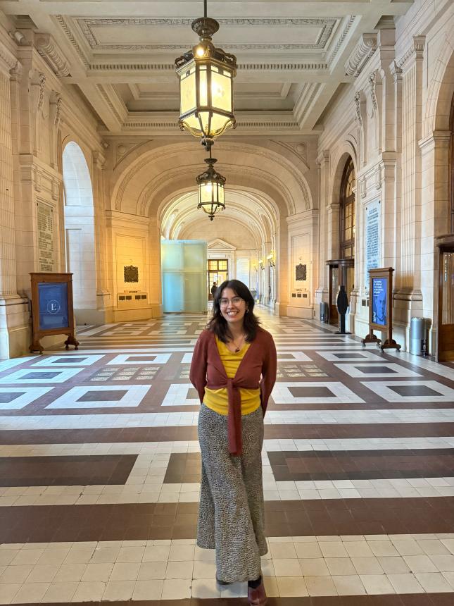 Amelia in ornate hallway with arches, lanterns, and patterned tile floor.