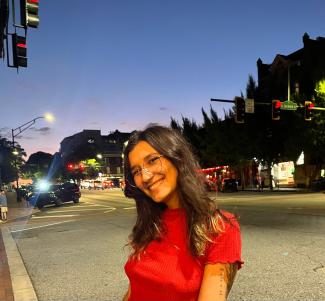 A woman wearing a red blouse and glasses smiles for a picture